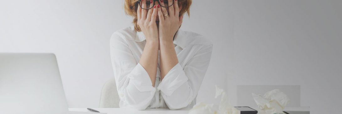 Frau mit weißer Bluse und Brille frustriert