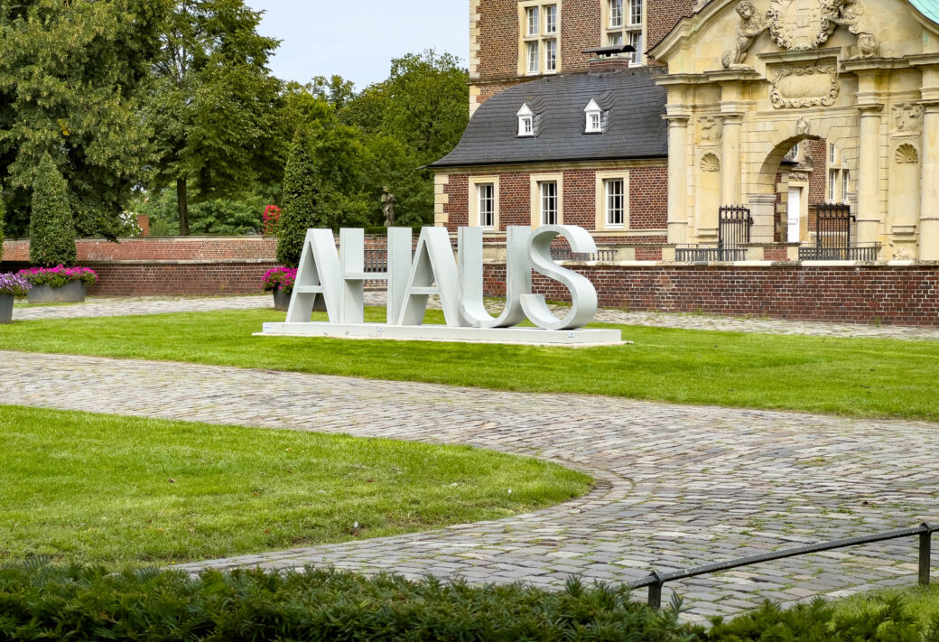 Grosses Ahaus-Schild vor historischem Stadtgebäude