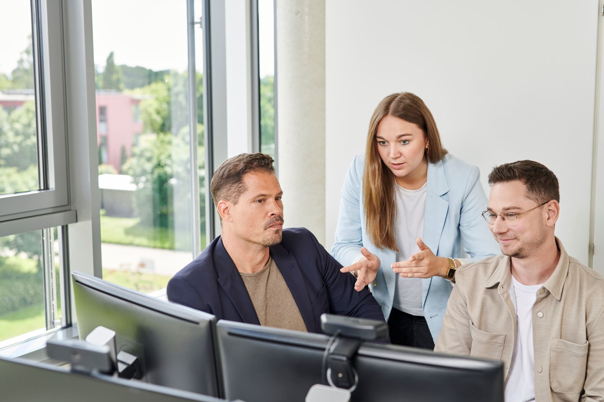 3 Mitarbeitende befinden sich in einer Besprechung vor dem PC.