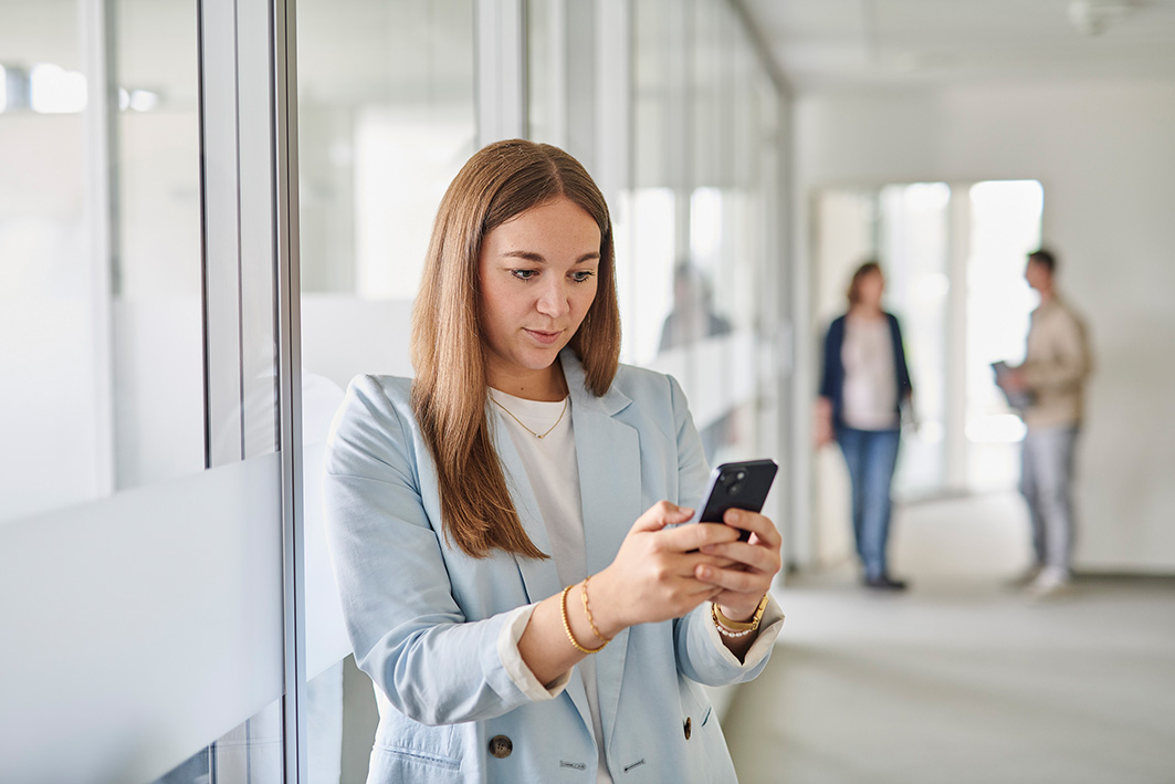 Eine Mitarbeiterin sieht sich auf dem Smartphone eine elektronische Signatur Software an